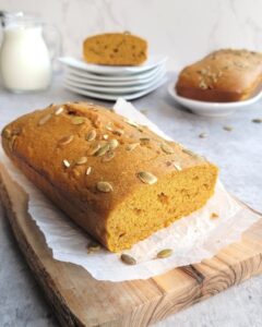 Golden pumpkin bread with pumpkin seeds sprinkled on top, freshly baked and sliced.