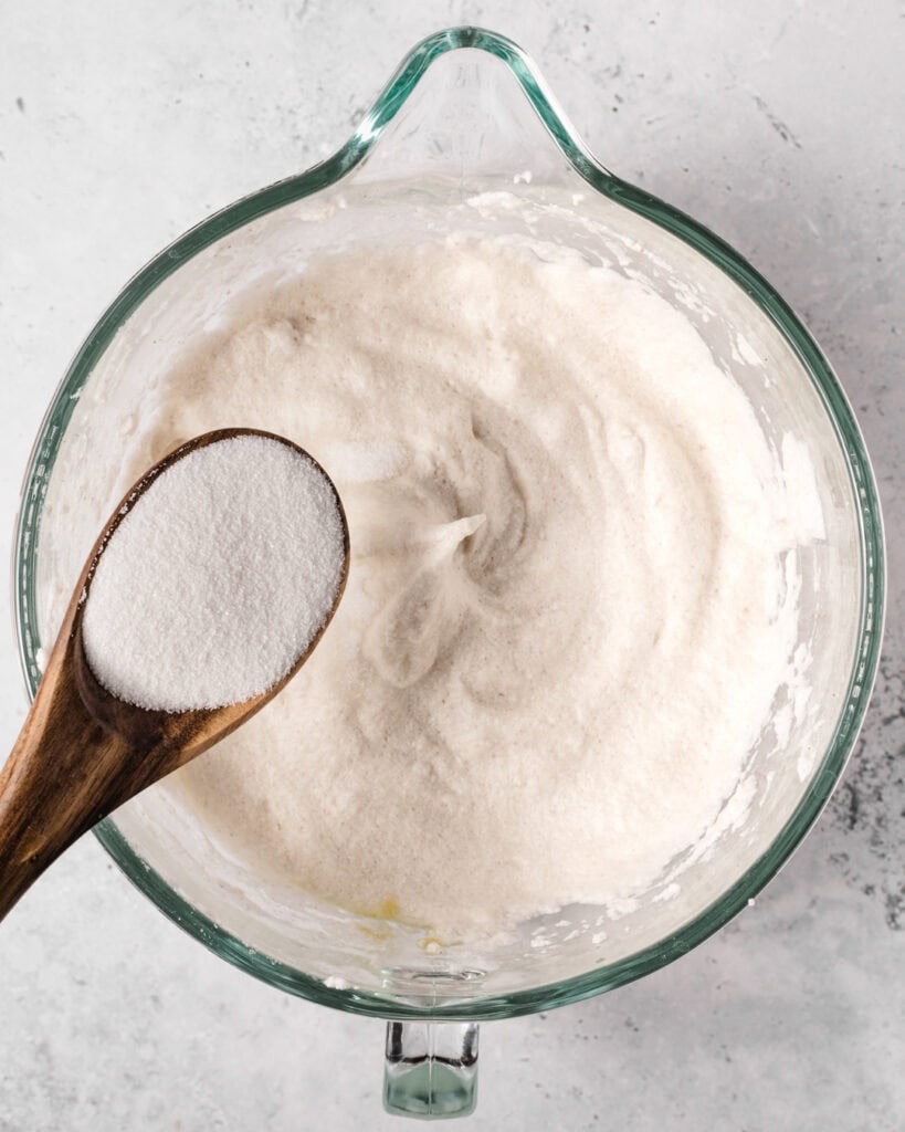 A bowl of flour with a wooden spoon containing more flour, ready for baking.