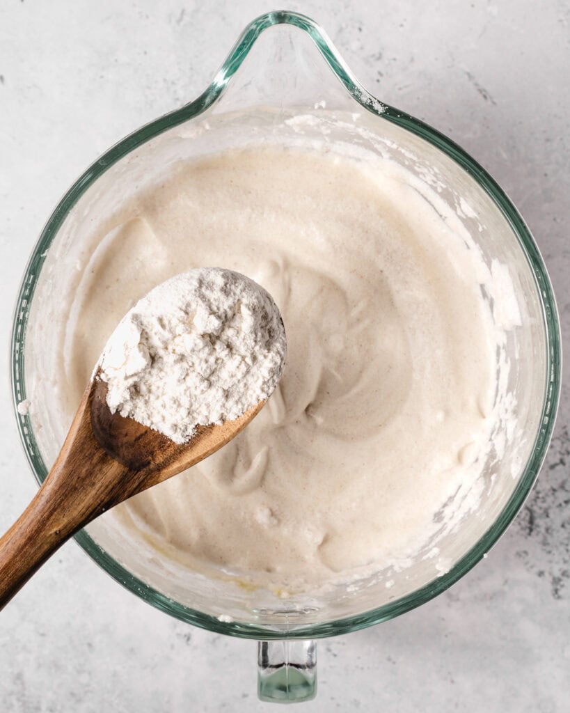 Creamy sponge cake batter in a glass bowl with a wooden spoon.