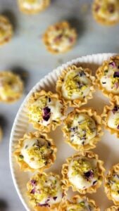 Butterscotch caramel chocolates with edible flower topping, displayed on a white plate.
