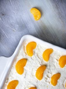 Sweet orange slices topped on creamy dessert in white dish.