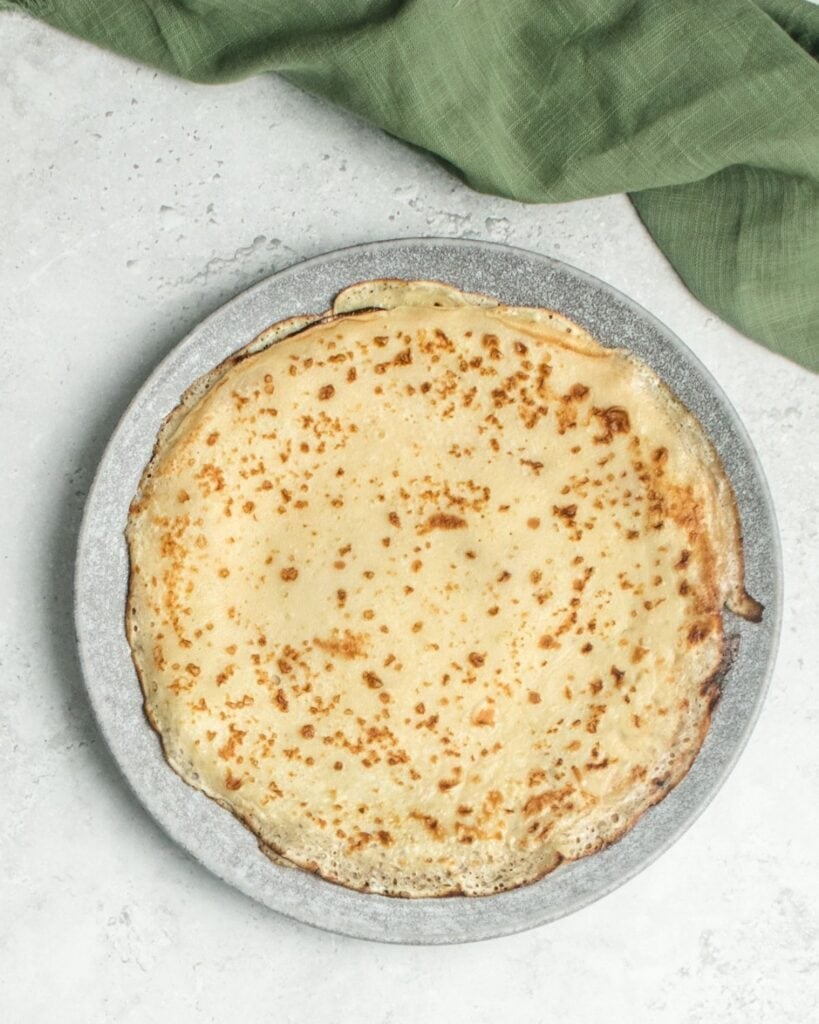 Delicious Somali Malawah crepe with golden-brown surface on a gray plate.