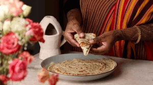 reshly made malawah being folded in a kitchen with colorful striped attire.