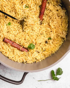 A close-up of Somali Bariis rice dish with cinnamon sticks and fresh herbs.