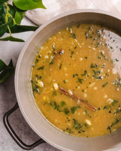 Soup made with spices, herbs, and vegetables in a large pot.