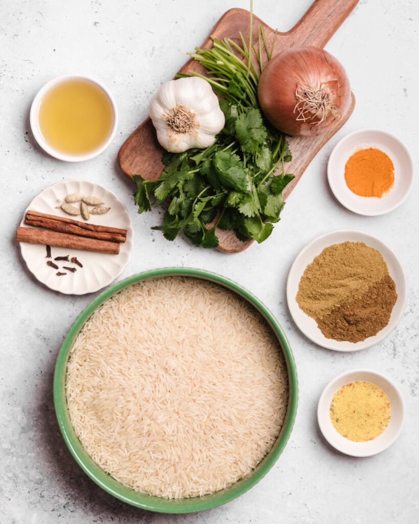 Ingredients for Somali Bariis including rice, onions, garlic, spices, herbs, and oil.