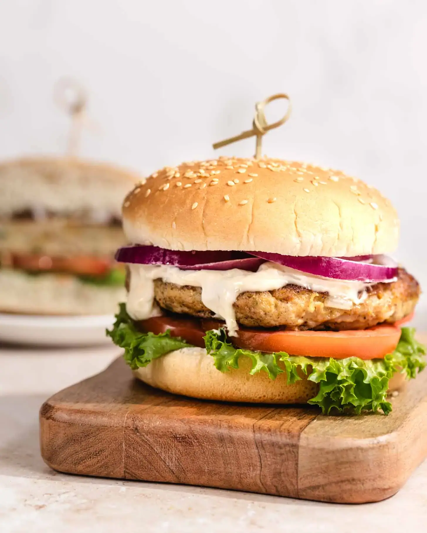 Juicy chicken burger with lettuce, tomato, onion, and sauce on a sesame bun.