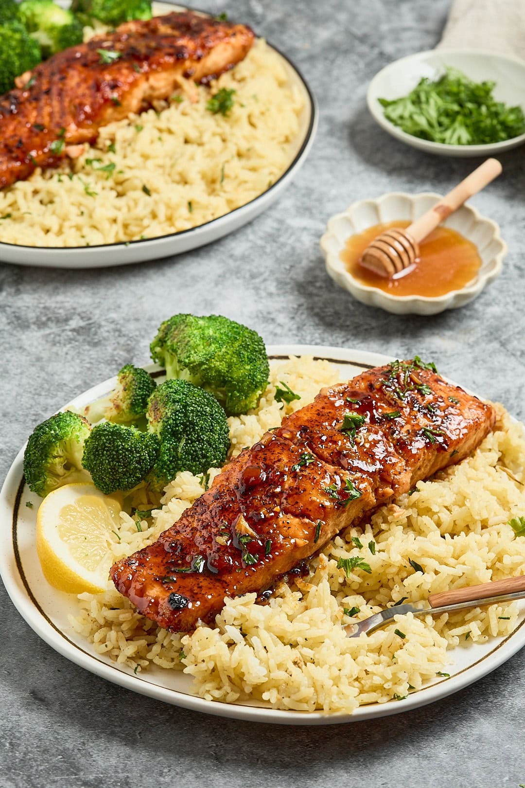 Grilled salmon fillet on rice with broccoli and lemon wedge.