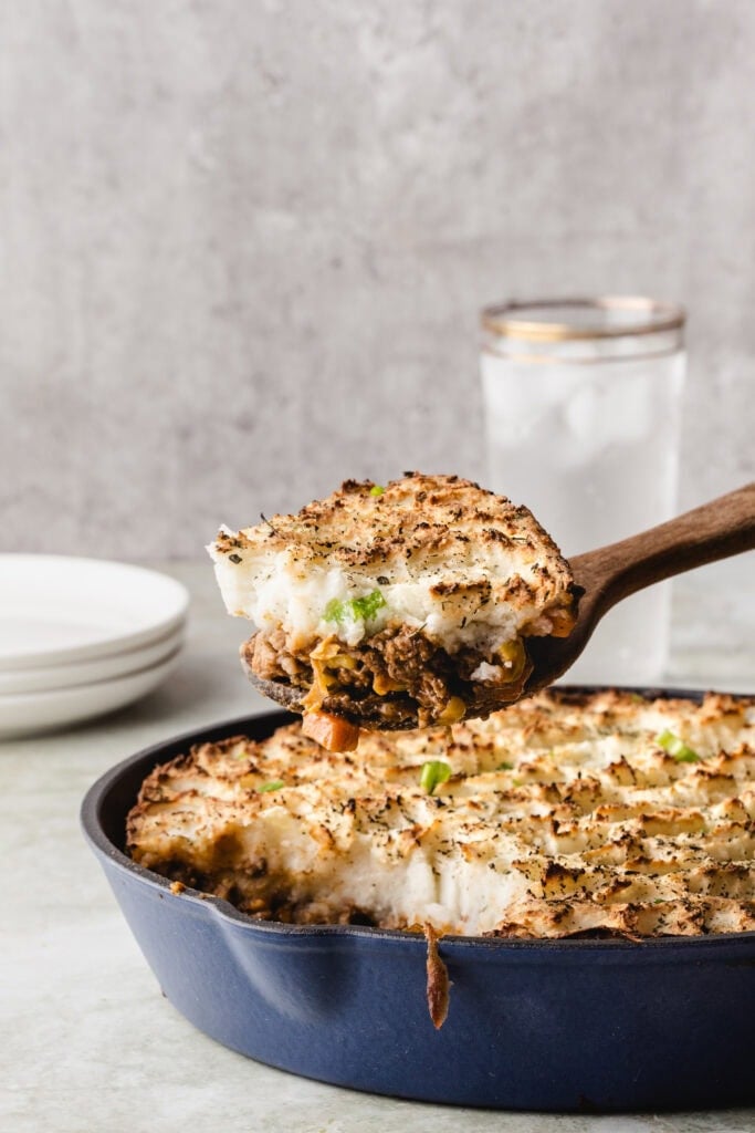 A spoonful of shepherd's pie showing mashed potato topping and meat filling.