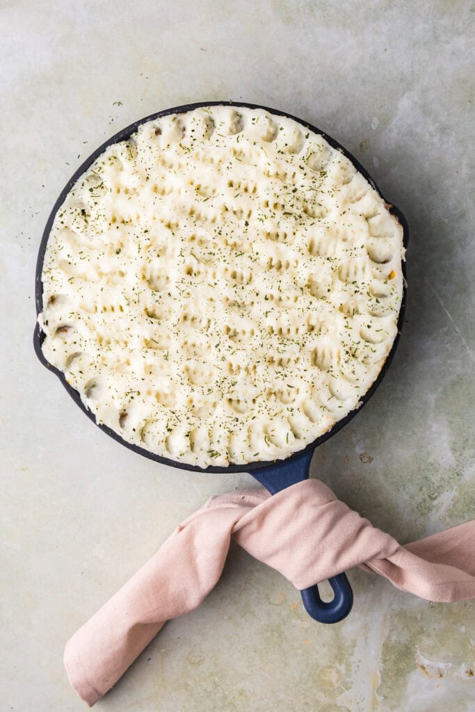 Close-up of a cheese pizza in a skillet with melted cheese and golden crust.