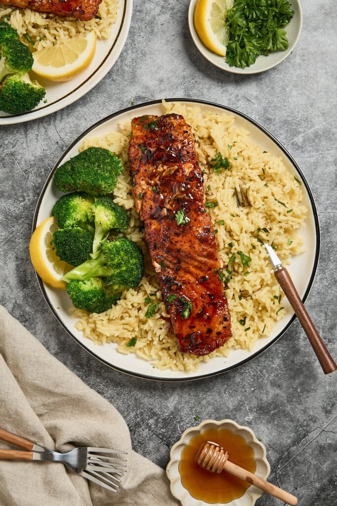 Grilled salmon fillet on rice with broccoli and lemon slices.