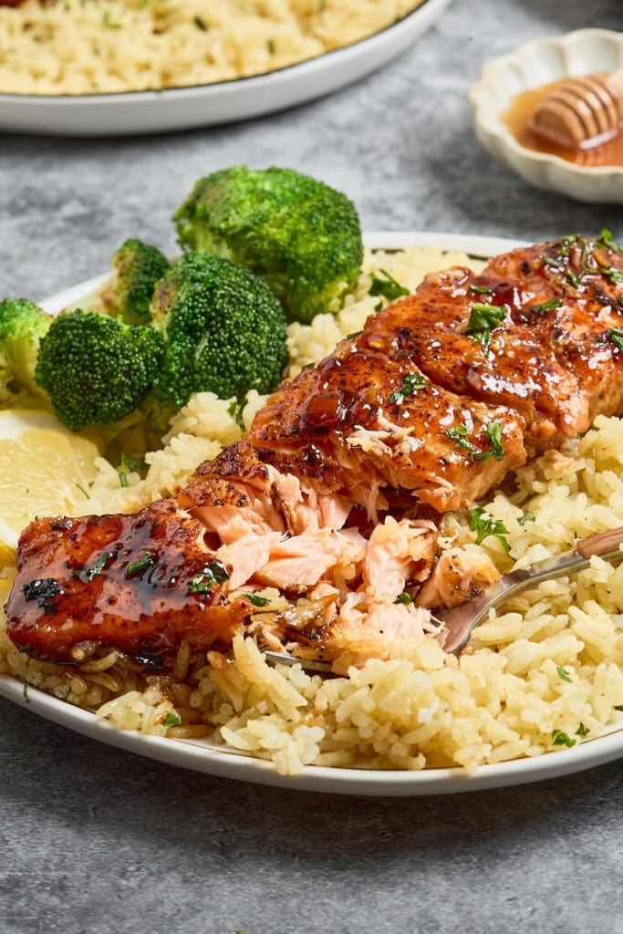 Baked salmon fillet with broccoli and rice on a white plate.